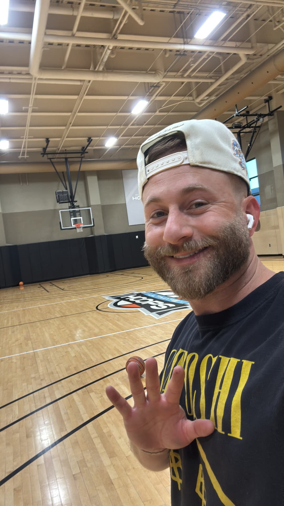 Landon, smiling and waving in a basketball gym in Phoenix.